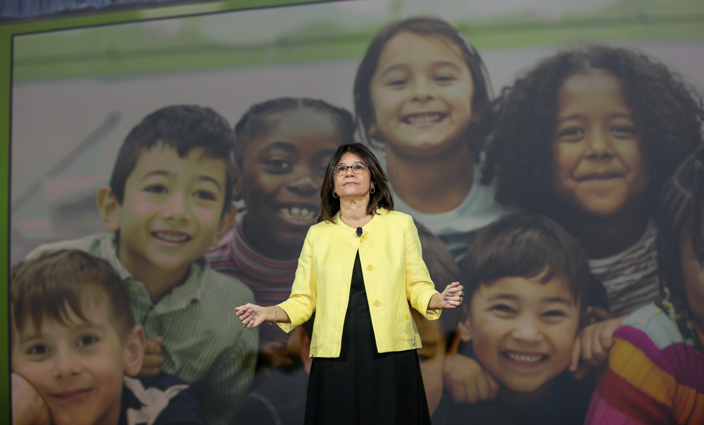 gladys cruz on stage in front of projected photo of kids