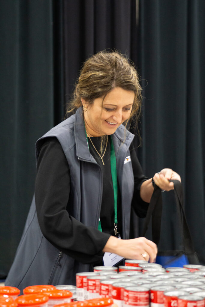 A 2023 conference attendee picks canned soup to stuff in donated bags. Photo by Paige Heller.