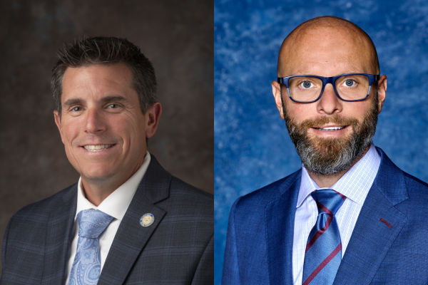 two headshots side by side. On the left, a white man with dark brown hair in a gray suit and blue tie. On the right, a white bald man with glasses and a beard wearing a blue suit and tie.